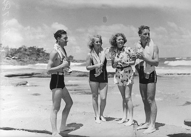A black and white photo of two young men and two young women standing on a beach in 1938, looking toward the ocean.