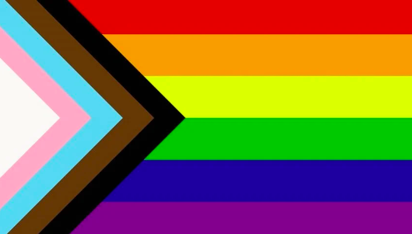An intersectional pride flag, with the horizontal rainbow rows punctuated triangles of black, brown, blue, pink, and white, to represent BIPOC and trans communities.